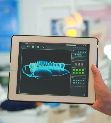 Hand holding a tablet displaying a 3D dental X-ray scan interface